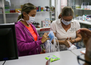 Pharmacy clerks count face masks to sell, as Venezuelans rush to buy hand sanitizers and masks in the face of the global COVID-19 coronavirus pandemic, in Caracas, on March 13, 2020. (Photo by CRISTIAN HERNANDEZ / AFP)