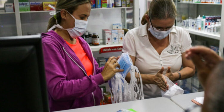 Pharmacy clerks count face masks to sell, as Venezuelans rush to buy hand sanitizers and masks in the face of the global COVID-19 coronavirus pandemic, in Caracas, on March 13, 2020. (Photo by CRISTIAN HERNANDEZ / AFP)