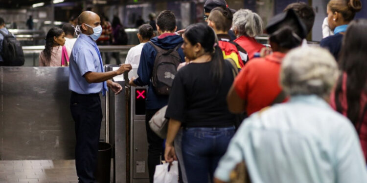 A subway worker wearing a face mask (L) receive tickets at the subway station in the face of the global COVID-19 coronavirus pandemic, in Caracas, on March 13, 2020. (Photo by CRISTIAN HERNANDEZ / AFP)