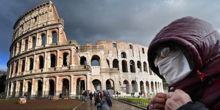 A man wearing a protective mask passes by the Coliseum in Rome on March 7, 2020 amid fear of Covid-19 epidemic. - Italy on March 6, 2020 reported 49 more deaths from the new coronavirus, the highest single-day toll to date, bringing the total number of fatalities over the past two weeks to 197. (Photo by Alberto PIZZOLI / AFP)