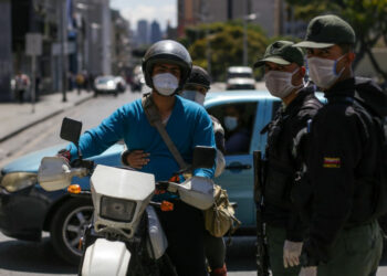 Members of the Bolivarian National Guard (R) block an avenue wearing face masks as a precautionary measure against the spread of the new coronavirus, COVID-19, in Caracas, on March 17, 2020 - President Nicolas Maduro asked the International Monetary Fund on Tuesday for a $5 billion loan to help crisis-worn Venezuela cope with the onslaught of the coronavirus. (Photo by Cristian Hernandez / AFP)