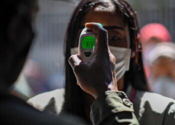 A member of the Bolivarian National Guard checks a woman's temperature as a preventive measure against the spread of the new coronavirus, COVID-19, outside a municipal market in Caracas, on March 20, 2020. (Photo by Federico PARRA / AFP)