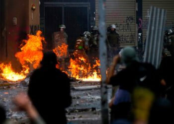 Riot police are reached by a petrol bomb during clashes with demonstrators protesting, in Santiago, on November 8, 2019. - Unrest began in Chile last October 18 with protests against a rise in transport tickets and other austerity measures that descended into vandalism, looting, and clashes between demonstrators and police. (Photo by JAVIER TORRES / AFP)