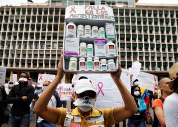 A woman carrying empty medication containers takes part in a protest due to the shortages of medicines outside the Health Ministry in Caracas, Venezuela April 18, 2018. The placard reads, "Shortage in antiretroviral medications". REUTERS/Carlos Garcia Rawlins