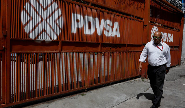 Foto de archivo de un hombre pasando por una puerta con el logotipo corporativo de la petrolera estatal venezolana PDVSA en Caracas. 3 de noviembre de 2017. REUTERS/Marco Bello
