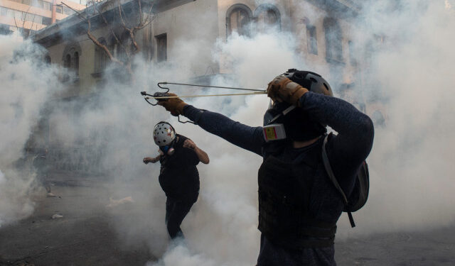 A demonstrators aims a sling at the police during a protest against Chilean President Sebastian Pinera's government in Santiago on March 02, 2020. (Photo by Martin BERNETTI / AFP)