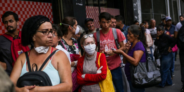 People queue to enter a super market in the face of the global COVID-19 coronavirus pandemic, in Caracas, on March 13, 2020. (Photo by CRISTIAN HERNANDEZ / AFP)