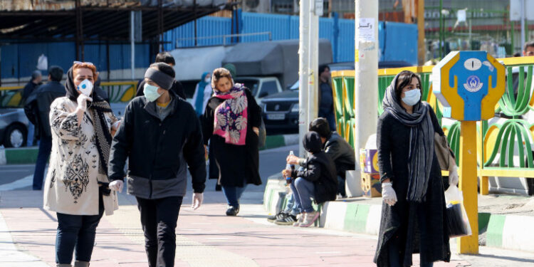 Iranian pedestrians walk while wearing protective masks in Tehran on March 10, 2020 amid the spread of coronavirus in the country. - Iran today reported 54 new deaths from the novel coronavirus in the past 24 hours, the highest single-day toll since the start of the country's outbreak. (Photo by ATTA KENARE / AFP)