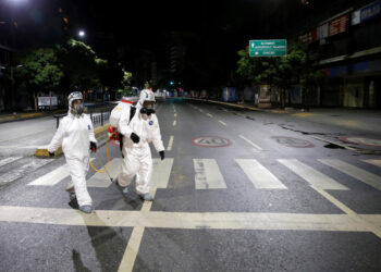Workers in protective suits walk on the street during the national quarantine in response to the spread of coronavirus disease (COVID-19) in Caracas, Venezuela, March 21, 2020. REUTERS/Manaure Quintero