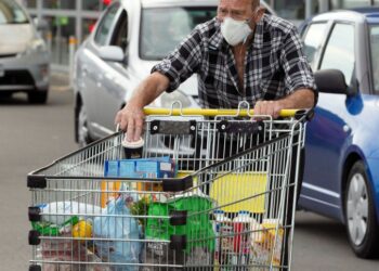 Brian Green, 76, wears a mask as he takes out products from his supermarket shopping cart and load them into his car outside Pak'nSave supermarket amid the spread of the coronavirus disease (COVID-19) in Christchurch, New Zealand, March 23, 2020. REUTERS/Martin Hunter