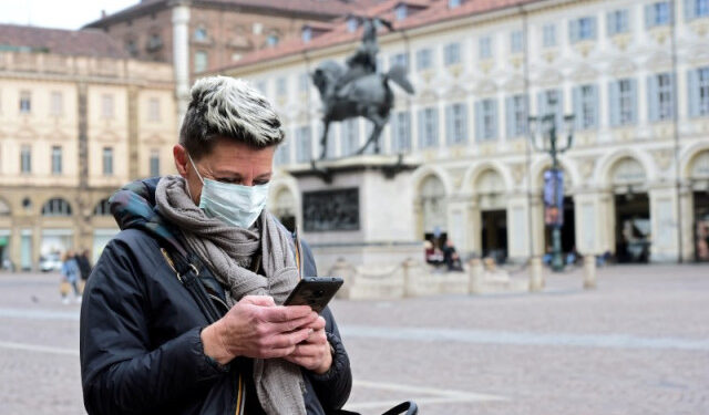 Imagen de archivo de una mujer utilizando una mascarilla mientras mira su teléfono, en momentos en que el brote de coronavirus sigue expandiéndose en Turín, en el norte de Italia. 27 de febrero, 2020. REUTERS/Massimo Pinca