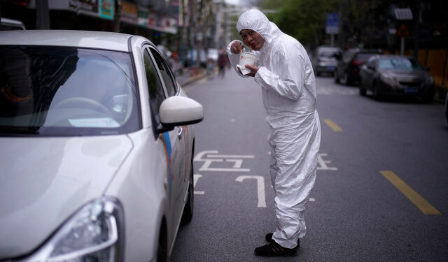 A man wearing a protective suit eats his breakfast,?Regan Noodle?, a Wuhan signature dish of hot dried noodles, on a street in Wuhan, Hubei province, the epicenter of China's coronavirus disease (COVID-19) outbreak, April 2, 2020. REUTERS/Aly Song