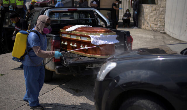 A worker sprays disinfectant on a vehicle carrying a coffin lined up to enter a cemetery as Ecuador's government announced on Thursday it was building a "special camp" in Guayaquil for coronavirus disease (COVID-19) victims, in Guayaquil, Ecuador April 2, 2020. REUTERS/Vicente Gaibor del Pino NO RESALES. NO ARCHIVES