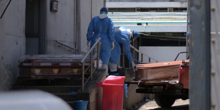 Health workers wearing protective gear load coffins outside of Teodoro Maldonado Carbo Hospital amid the spread of the coronavirus disease (COVID-19), in Guayaquil, Ecuador April 3, 2020. Picture taken April 3, 2020. REUTERS/Vicente Gaibor del Pino NO RESALES. NO ARCHIVES