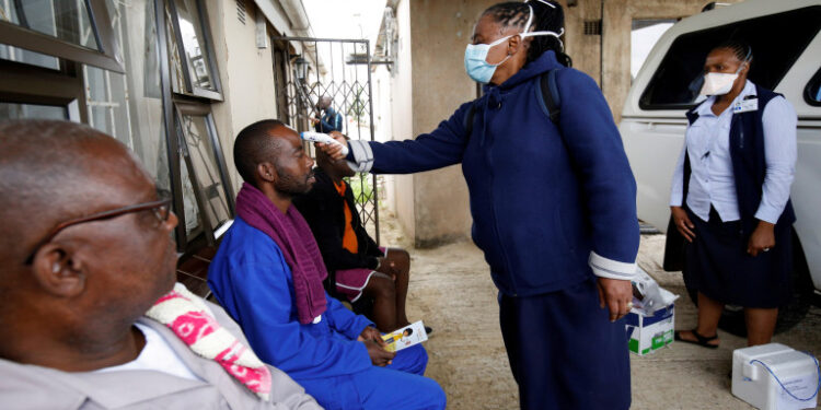 FILE PHOTO: A health worker checks a man's temperature during a door-to-door testing in an attempt to contain the coronavirus disease (COVID-19) outbreak, in Umlazi township near Durban, South Africa, April 4, 2020. REUTERS/Rogan Ward/File Photo