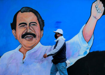 Un hombre con mascarilla para protegerse del coronavirus camina junto a un mural que representa al presidente nicaragüense Daniel Ortega, en Managua, Nicaragua. 30 de marzo de 2020.  REUTERS/Oswaldo Rivas