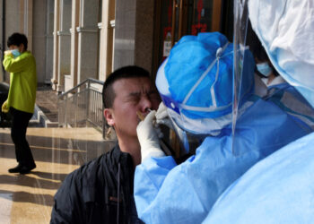 A worker from the city's center for disease control and prevention takes a swab from a man to test for the coronavirus disease (COVID-19) in Suifenhe, a city bordering Russia in China's Heilongjiang province, April 16, 2020. REUTERS/Huizhong Wu