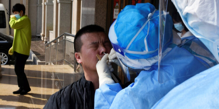 A worker from the city's center for disease control and prevention takes a swab from a man to test for the coronavirus disease (COVID-19) in Suifenhe, a city bordering Russia in China's Heilongjiang province, April 16, 2020. REUTERS/Huizhong Wu