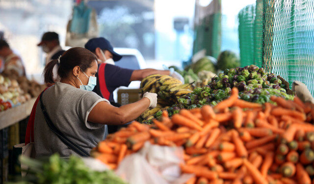 Una mujer que lleva una máscara protectora escoge verduras en un mercado callejero durante la cuarentena nacional en respuesta a la propagación de la enfermedad por coronavirus (COVID-19), en Caracas. 31 de marzo de 2020. REUTERS/Fausto Torrealba NO DISPONIBLE PARA REVENTA NI ARCHIVO.