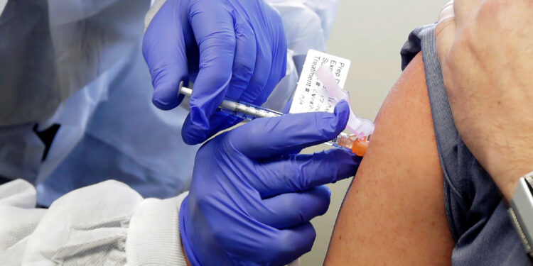 Neal Browning receives a shot in the first-stage safety study clinical trial of a potential vaccine for COVID-19, the disease caused by the new coronavirus, Monday, March 16, 2020, at the Kaiser Permanente Washington Health Research Institute in Seattle. Browning is the second patient to receive the shot in the study. (AP Photo/Ted S. Warren)