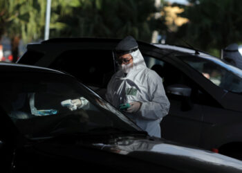 A nurse measures the temperature of a man during drive-thru triage to identify people with coronavirus disease (COVID-19) symptoms in Guarulhos, Sao Paulo state, Brazil, April 3, 2020. REUTERS/Amanda Perobelli