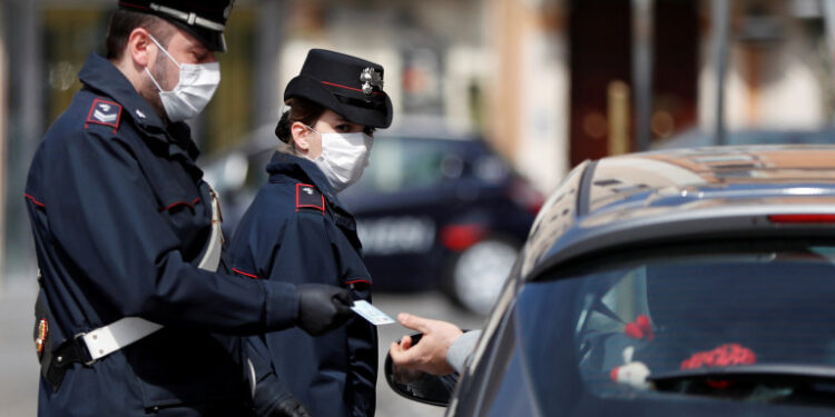 Carabinieri wearing protective face masks verify if a driver has a valid reason to travel during the lockdown to prevent the spread of coronavirus disease (COVID-19), at Piazza Venezia in Rome, Italy, March 21, 2020. REUTERS/Yara Nardi