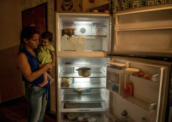Wuendy Perez, a single mother with five children, with her youngest daughter, Wuendy Joselin, 1, next to their nearly empty refrigerator, in La Guaira, Venezuela, June 16, 2017. The economic collapse has taken a large toll on the economy and people here, leaving residents struggling to make ends meet amid widespread shortages and soaring food prices. (Meridith Kohut/The New York Times) 
CONTACTO