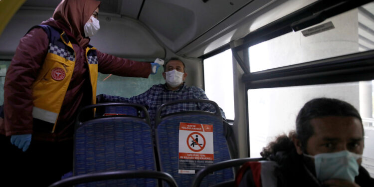 The medic checks the temperature of a passenger in a bus on a highway near Istanbul after the government decided to shut down the borders of  31 cities for all vehicles excluding transit passage for essential supplies, as the spread of coronavirus disease (COVID-19) continues, at the outskirts of Istanbul, Turkey April 4, 2020. REUTERS/Umit Bektas
