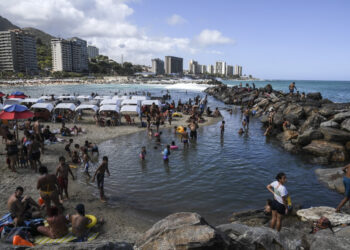 People enjoy Camurichico beach in La Guaira, Vargas state, Venezuela, on January 12, 2020. - With rum, reggaeton and "no change" on the horizon, Venezuelans go to the beach after a week of protests and disputes in the National Assembly. (Photo by Yuri CORTEZ / AFP)