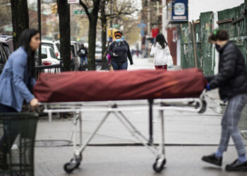 Manager Alisha Narvaez (L) and Lily Sage Weinrieb, Resident Funeral Director at International Funeral & Cremation Services transport a body on a stretcher to the funeral home on April 24, 2020, in the Harlem neighborhood of New York City. - For many families already in distress, finding a funeral home in New York that will accept the body of a loved one is a headache; in Harlem, International Funeral home tries not to turn anyone away, even if it means being under stress. (Photo by Johannes EISELE / AFP)