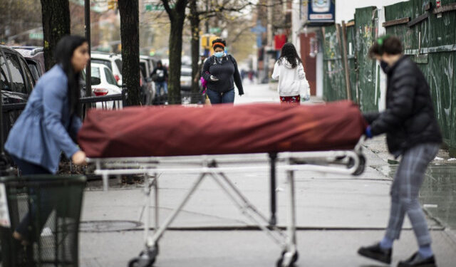 Manager Alisha Narvaez (L) and Lily Sage Weinrieb, Resident Funeral Director at International Funeral & Cremation Services transport a body on a stretcher to the funeral home on April 24, 2020, in the Harlem neighborhood of New York City. - For many families already in distress, finding a funeral home in New York that will accept the body of a loved one is a headache; in Harlem, International Funeral home tries not to turn anyone away, even if it means being under stress. (Photo by Johannes EISELE / AFP)