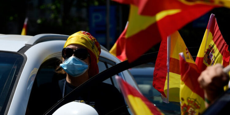 A protester honks from her car as she takes part in a "caravan for Spain and its freedom" protest by far-right party Vox against the government at the Plaza de Colon in Madrid on May 23, 2020. - Spain, one of the most affected countries in the world by the novel coronavirus with 28,628 fatalities, has extended until June 6 the state of emergency which significantly limits the freedom of movement to fight the epidemic. The left-wing government's management of the crisis has drawn a barrage of criticism from righ-wing parties who have denounced its "brutal confinement". (Photo by JAVIER SORIANO / AFP)
