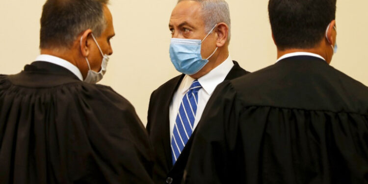 Israeli Prime Minister Benjamin Netanyahu (C), wearing a protective face maks, is pictured inside a courtroom at the district court of Jerusalem on May 24, 2020, during the first day of his corruption trial. - Fresh from forming a new government after more than 500 days of electoral deadlock, Netanyahu is expected to begin a new battle in the Jerusalem District Court -- to stay out of prison. The 70-year-old was scheduled to appear at a court hearing to formally confirm his identity to judges, after being indicted in January for bribery, fraud and breach of trust. (Photo by RONEN ZVULUN / POOL / AFP)