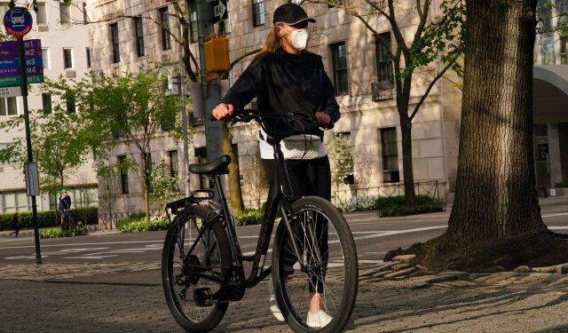 NEW YORK, NY - MAY 04: A woman walks a bike while wearing a protective mask during the coronavirus pandemic on May 4, 2020 in New York City. COVID-19 has spread to most countries around the world, claiming over 252,000 lives with over 3.6 million infections reported.   Cindy Ord/Getty Images/AFP