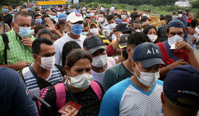 People wearing protective face masks line up to cross the border between Colombia and Venezuela at the Simon Bolivar international bridge, after the World Health Organization has described the outbreak as a pandemic, in Cucuta, Colombia March 12, 2020.  REUTERS/Carlos Eduardo Ramirez