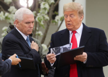 U.S. President Donald Trump speaks with Vice President Mike Pence while holding a photo of New York City Mayor Bill de Blasio before the start of a Fox News "virtual town hall" event on the coronavirus (COVID-19) outbreak with members of the coronavirus task force in the Rose Garden of the White House in Washington, U.S., March 24, 2020. REUTERS/Jonathan Ernst