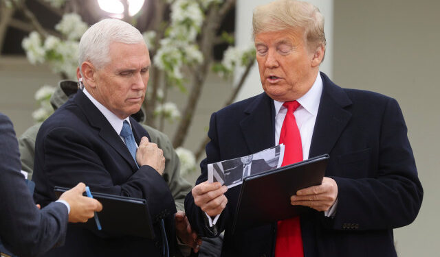 U.S. President Donald Trump speaks with Vice President Mike Pence while holding a photo of New York City Mayor Bill de Blasio before the start of a Fox News "virtual town hall" event on the coronavirus (COVID-19) outbreak with members of the coronavirus task force in the Rose Garden of the White House in Washington, U.S., March 24, 2020. REUTERS/Jonathan Ernst