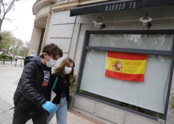 Marco Donoso del Bufalo, 20, a young man on the autism spectrum, and his sister Irene, 22, walk past a Spanish flag that reads "Come on, Spain. Together we will succed" as they take their daily walk during the lockdown amid the coronavirus disease (COVID-19) outbreak in Madrid, Spain, April 9, 2020. Picture taken April 9, 2020. REUTERS/Susana Vera