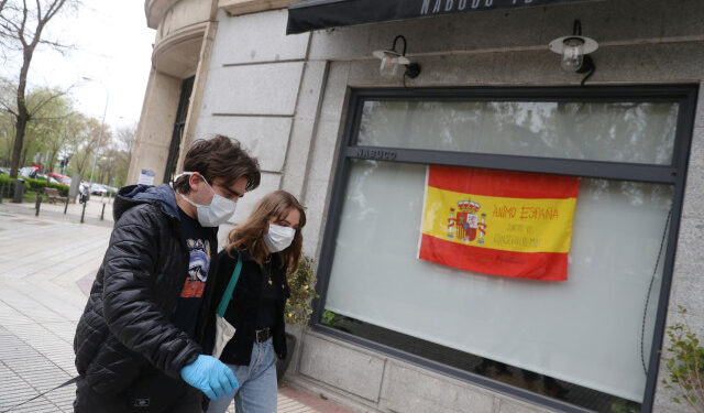 Marco Donoso del Bufalo, 20, a young man on the autism spectrum, and his sister Irene, 22, walk past a Spanish flag that reads "Come on, Spain. Together we will succed" as they take their daily walk during the lockdown amid the coronavirus disease (COVID-19) outbreak in Madrid, Spain, April 9, 2020. Picture taken April 9, 2020. REUTERS/Susana Vera