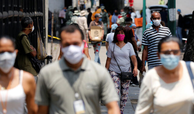 People wearing protective masks walk on a street during a nationwide quarantine as the spread of the coronavirus disease (COVID-19) continues, in Caracas, Venezuela April 20, 2020. REUTERS/Manaure Quintero