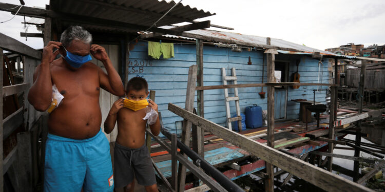 Foto de archivo de un hombre y un niño ajustándose sus máscaras en una barriada pobre en Manaus, Brasil, en medio de la pandemia de coronavirus.
May 19, 2020. REUTERS/Bruno Kelly