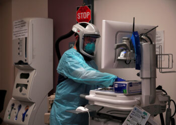 A healthcare worker wearing protective equipment looks at the computer in front of the room of a patient with coronavirus disease (COVID-19) at the El Centro Regional Medical Center in El Centro, California, U.S., May 27, 2020. Picture taken May 27, 2020. REUTERS/Ariana Drehsler NO RESALES. NO ARCHIVES