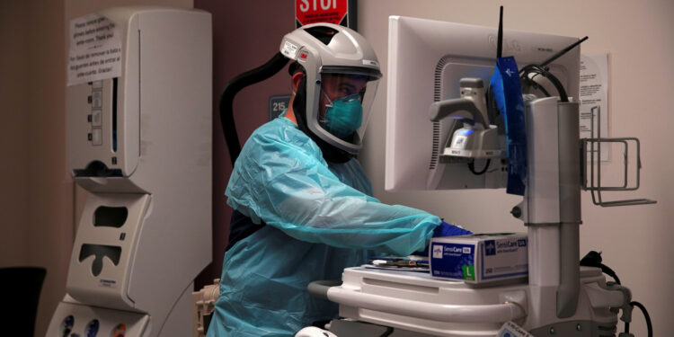 A healthcare worker wearing protective equipment looks at the computer in front of the room of a patient with coronavirus disease (COVID-19) at the El Centro Regional Medical Center in El Centro, California, U.S., May 27, 2020. Picture taken May 27, 2020. REUTERS/Ariana Drehsler NO RESALES. NO ARCHIVES