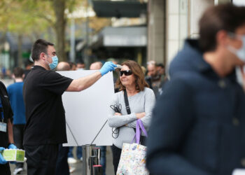 A customer has her temperature checked while waiting in line at an Apple Inc. store reopening, after being closed due to lockdown measures imposed because of the coronavirus, in the Bondi Junction suburb of Sydney, Australia, on Thursday, May 7, 2020. Apple's app store saw its strongest month of growth in two and a half years in April, according to Morgan Stanley, which wrote that "all major regions & categories saw accelerating spend" as a result of the pandemic. Photographer: Brendon Thorne/Bloomberg