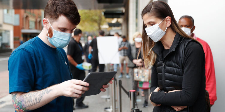An employee assists a customer, both wearing protective masks, waiting in-line at an Apple Inc. store reopening, after being closed due to lockdown measures imposed because of the coronavirus, in the Bondi Junction suburb of Sydney, Australia, on Thursday, May 7, 2020. Apple's app store saw its strongest month of growth in two and a half years in April, according to Morgan Stanley, which wrote that "all major regions & categories saw accelerating spend" as a result of the pandemic. Photographer: Brendon Thorne/Bloomberg