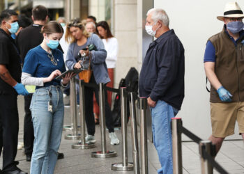 An employee assists a customer, both wearing protective masks, waiting in-line at an Apple Inc. store reopening, after being closed due to lockdown measures imposed because of the coronavirus, in the Bondi Junction suburb of Sydney, Australia, on Thursday, May 7, 2020. Apple's app store saw its strongest month of growth in two and a half years in April, according to Morgan Stanley, which wrote that "all major regions & categories saw accelerating spend" as a result of the pandemic. Photographer: Brendon Thorne/Bloomberg