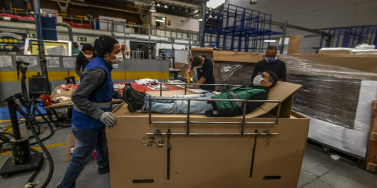 Workers assemble cardboard stretchers for clinics at a factory in Bogota on May 7, 2020, amid the new coronavirus pandemic. - Latin America and the Caribbean on Thursday exceeded 300,000 cases of the new coronavirus, which has caused the death of 16,293 people in the region, according to an AFP balance sheet prepared with official data. (Photo by Juan BARRETO / AFP)