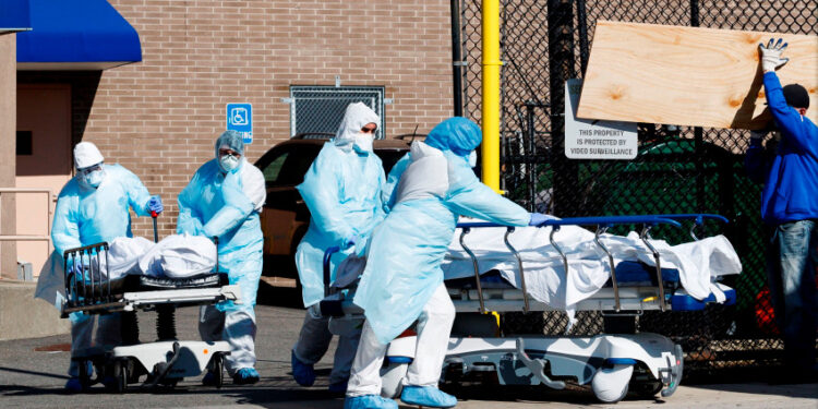 Healthcare workers transport two bodies past a construction worker building the interiors of one of two temporary morgues set up outside of the Wyckoff Heights Medical Center to handle the large number of victims of the COVID-19 disease in Brooklyn, New York, USA, 06 April 2020. EFE/EPA/JUSTIN LANE