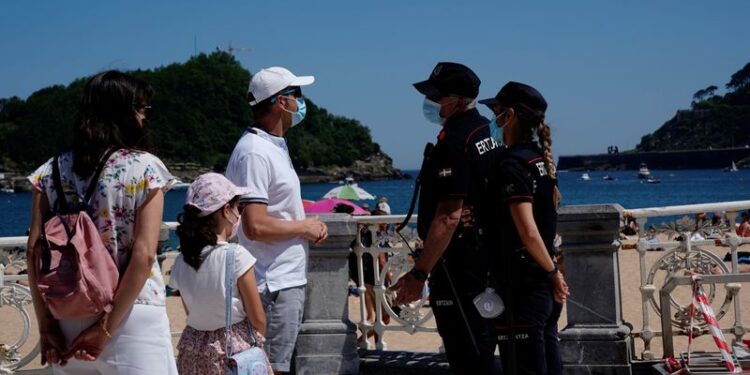 Una familia con mascarillas habla con la policía en la playa de Ondarreta en San Sebastián, España, el 30 de mayo, 2020. REUTERS/Vincent West