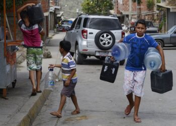 TO GO WITH AFP STORY by Gerardo Guarache
Boys carry empty bottles and cans to fill them with water in Caucaguita, Caracas, on June 20, 2014. Water use in Caracas and its suburbs, home to five million people, is being rationed since the beginning of May and will continue for two more months, due to drought. Even when fully operating and unaffected by drought, water supply levels in the capital area are below international standards, capable of providing 340 liters per person per day, which is sufficient for household consumption but falls short of commercial and industrial demands.  AFP PHOTO/Leo RAMIREZ